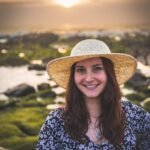 Smiling woman in a straw hat enjoys a beautiful sunset at Vila Nova de Gaia, Portugal.